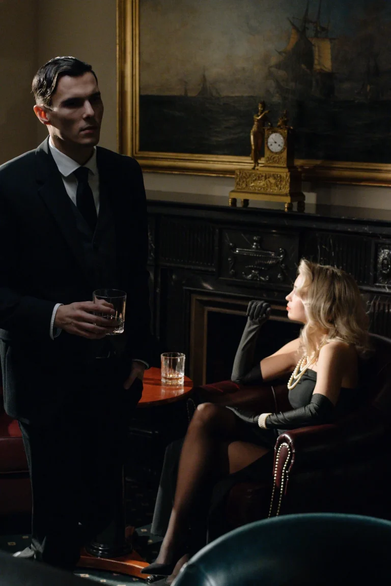 A man standing and a sexy woman sitting having drinks together