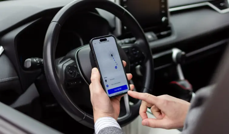 Man holding cell phone in car using GPS on cell phone.