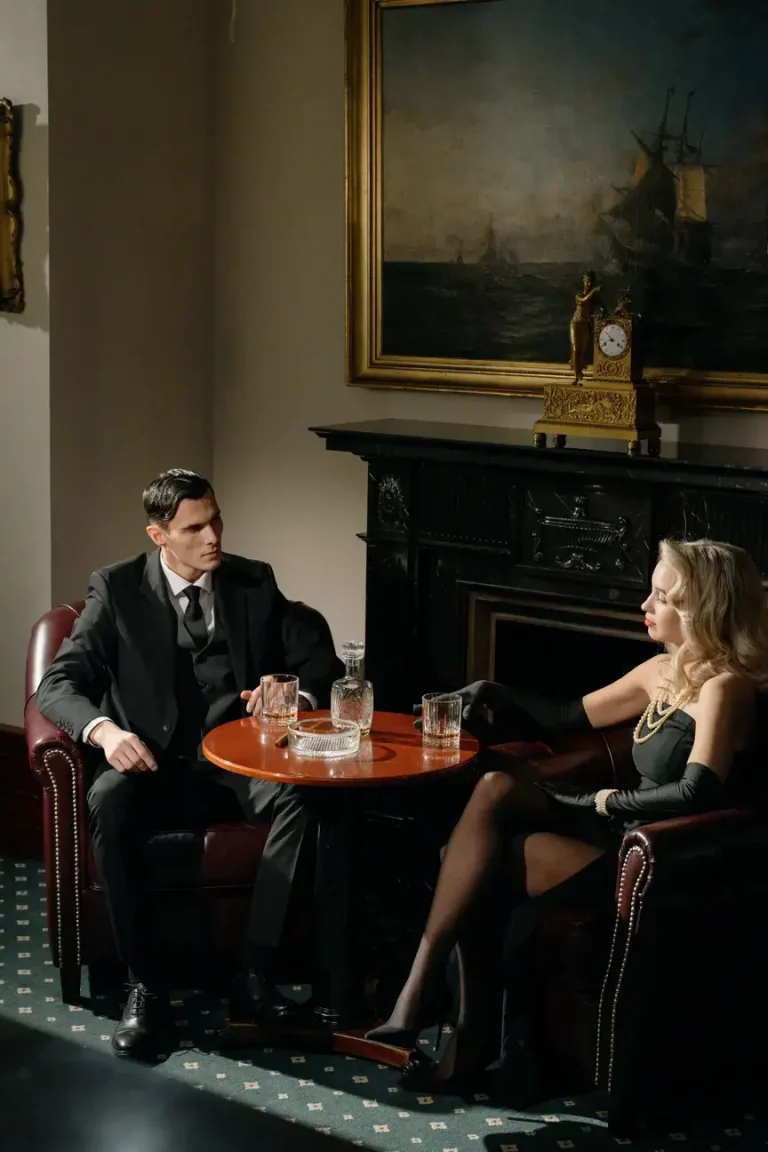 A man standing and a sexy woman sitting having drinks together